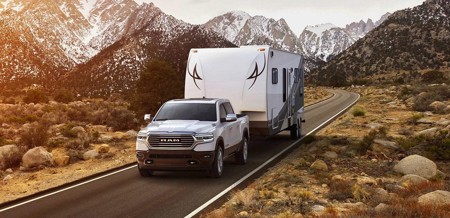 Image of a white 2019 RAM 1500 towing a trailer.